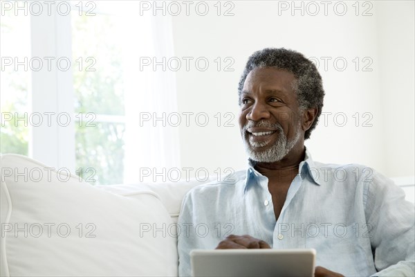 Senior man using digital tablet on sofa