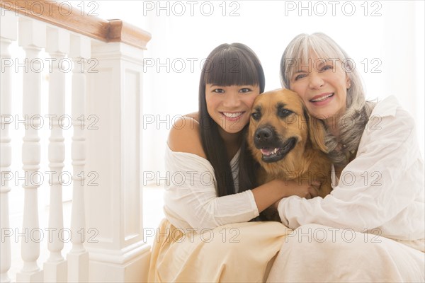 Mother and daughter hugging dog on steps