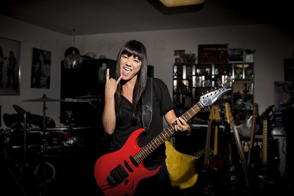 Woman playing electric guitar in basement