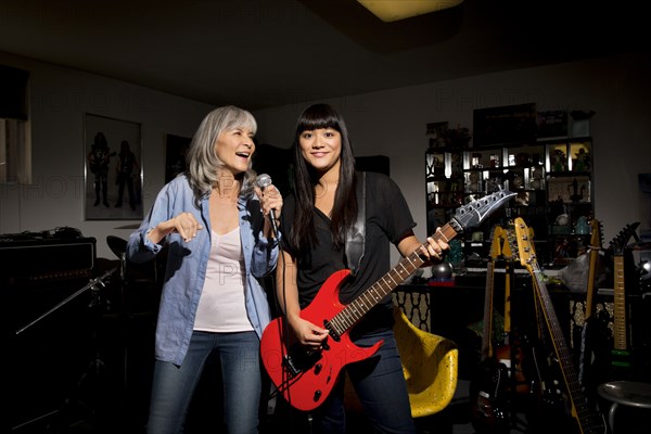 Mother and daughter singing and playing guitar in basement