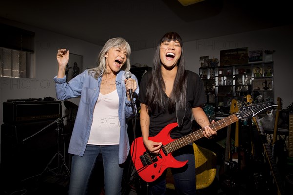 Mother and daughter playing music guitar in basement