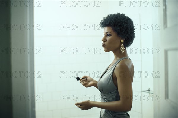 Woman putting on makeup in bathroom