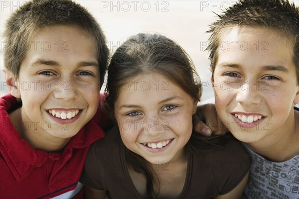 Hispanic twin brothers and sister hugging