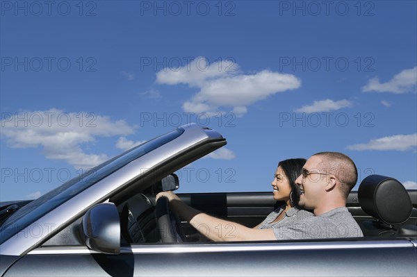 Multi-ethnic couple driving in convertible car