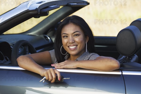 Asian woman sitting in convertible car