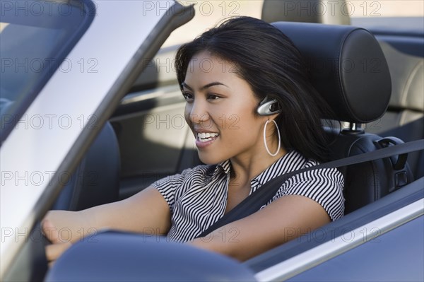 Asian woman driving convertible car