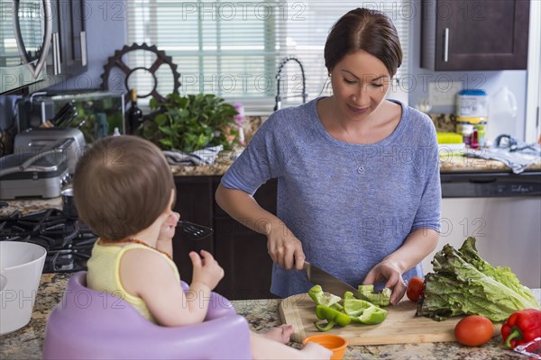 Mixed race mother chopping vegetables with daughter in kitchen