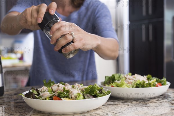 Mixed race woman seasoning salad