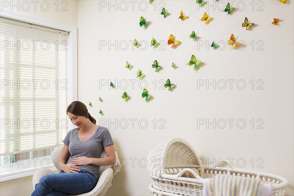 Mixed race pregnant woman sitting in nursery