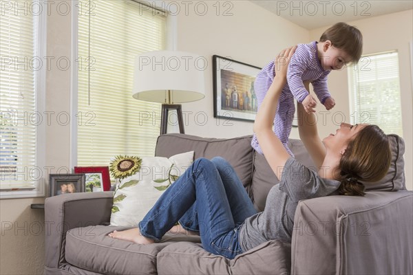 Mixed race mother playing with baby daughter on sofa