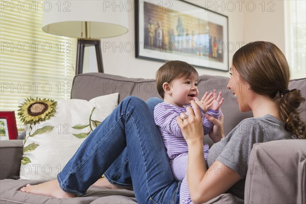 Mixed race mother playing with baby daughter on sofa