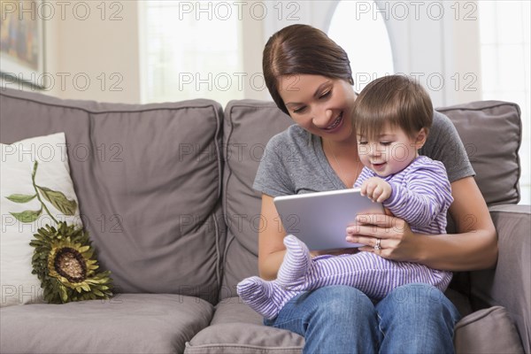 Mixed race mother and baby daughter using digital tablet