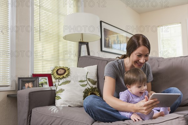 Mixed race mother and baby daughter using digital tablet