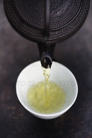 Close up of Japanese green tea being poured from teapot into cup