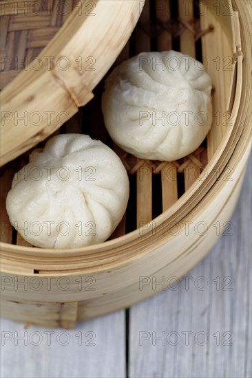Close up of steamed dim sum pork buns in bamboo basket