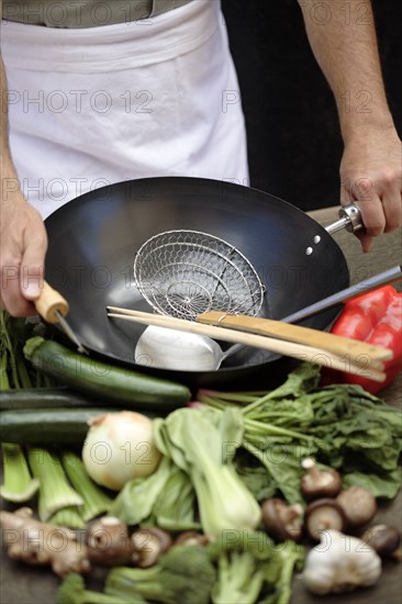 Caucasian chef with wok and fresh vegetables