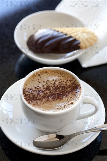 Close up of cup of coffee with cookie