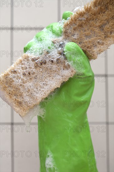 Close up of rubber glove holding sudsy cleaning brush