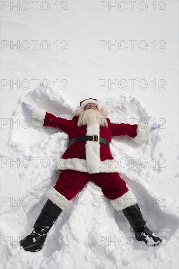 Santa Claus making snow angel outdoors