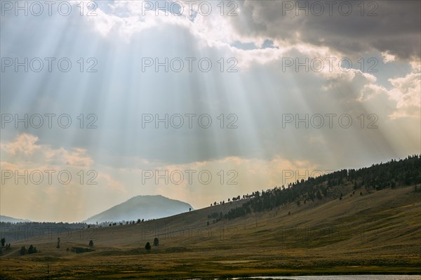 Sunbeams shining through clouds over rolling rural landscape