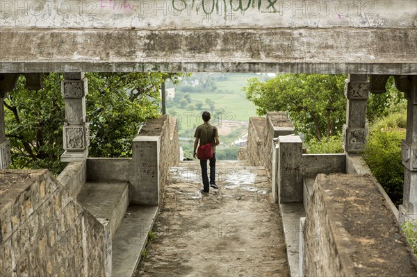 Man walking under stone walkway