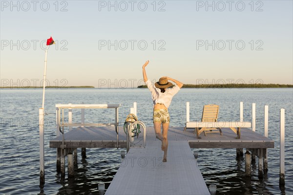 Caucasian woman jumping for joy on pier