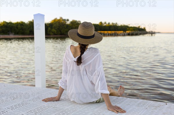 Caucasian woman sitting at edge of pier