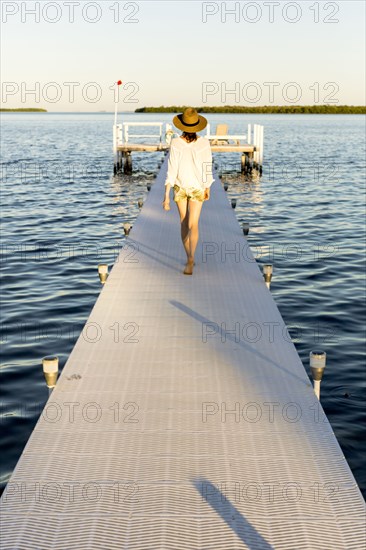 Caucasian woman walking on pier over water