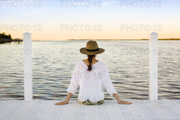Caucasian woman sitting at edge of pier