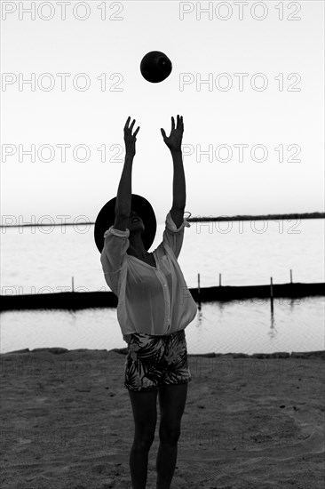 Caucasian woman playing with coconut on beach