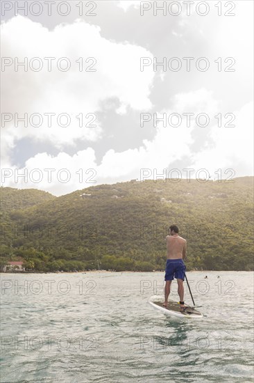 Caucasian man standing on paddle board on ocean