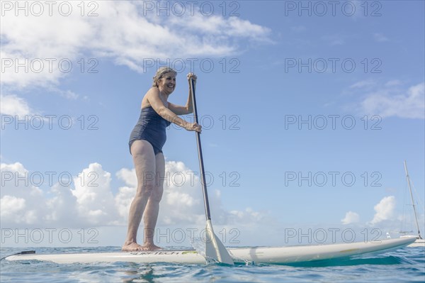 Caucasian woman standing on paddle board on ocean