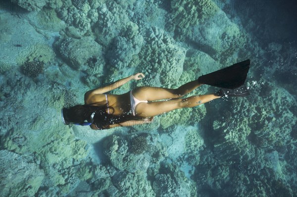 Mixed race woman snorkeling near tropical reef