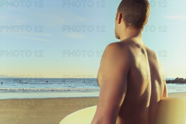 Mixed race man carrying surfboard on beach