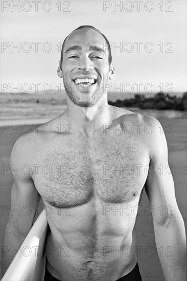 Mixed race man carrying surfboard on beach