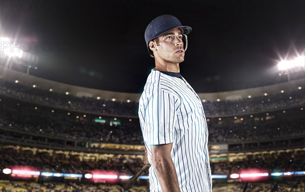 Mixed race baseball player standing in stadium