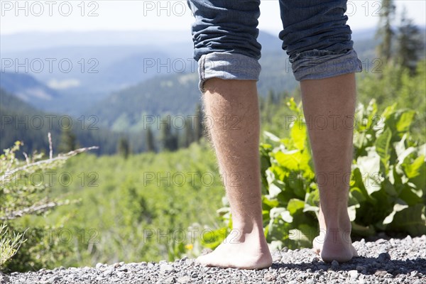 Barefoot Caucasian man standing near mountain landscape