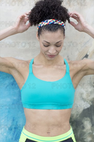 Mixed Race woman leaning on wall checking hair