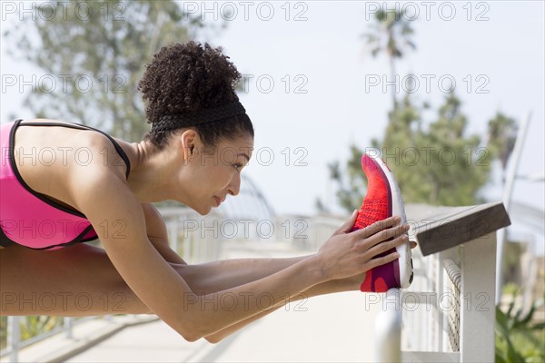 Mixed Race woman stretching leg on banister