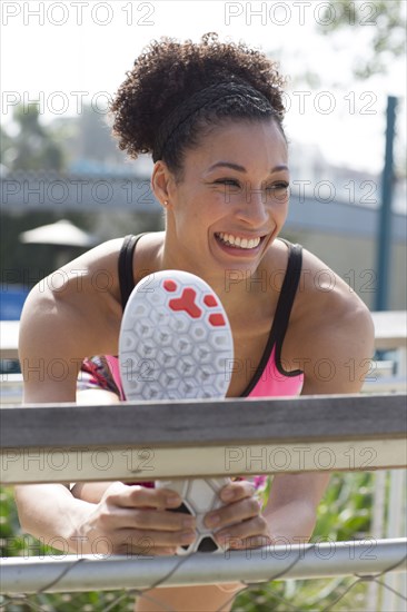 Mixed Race woman stretching leg on banister