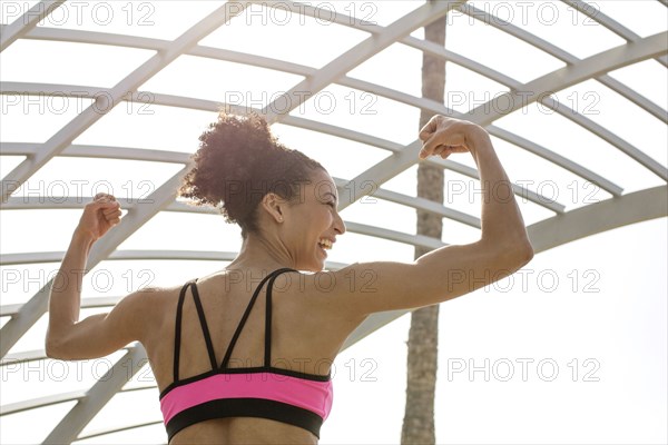 Mixed Race woman flexing arms