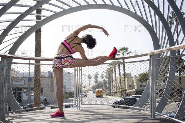 Mixed Race woman stretching leg on banister