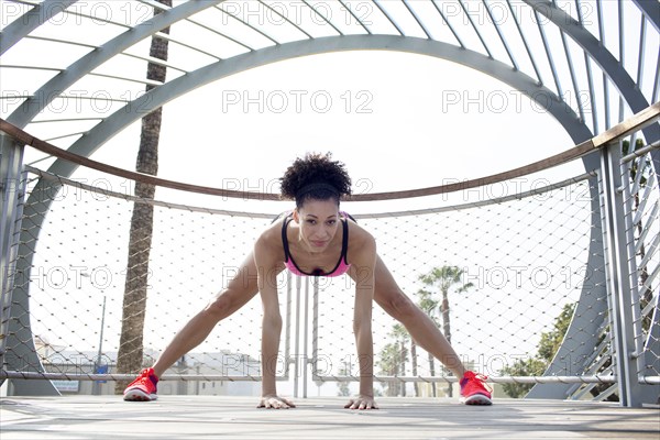 Mixed Race woman stretching leg near fence