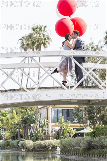 Kissing couple celebrating on bridge with balloons