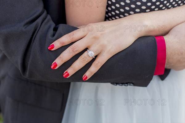 Man hugging woman wearing engagement ring on finger