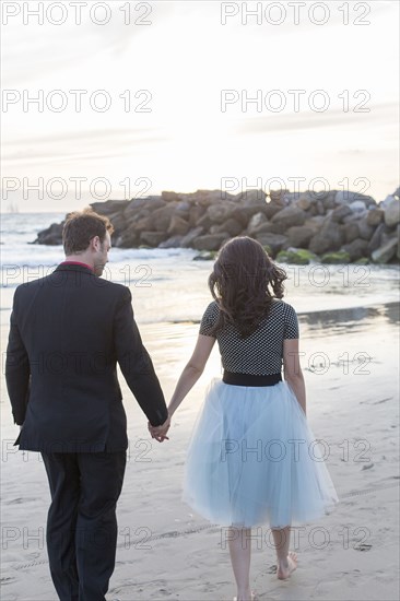 Couple holding hands and walking on beach