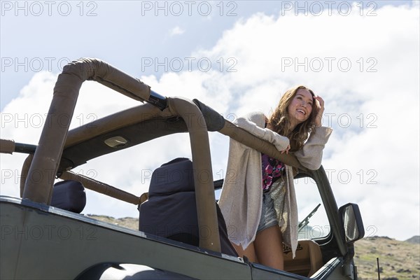 Mixed Race woman standing in convertible car