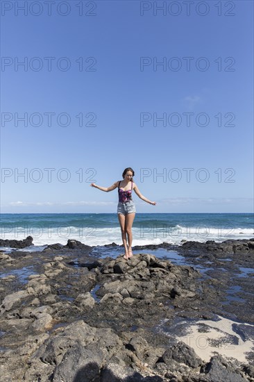 Mixed Race woman standing on rocks on beach