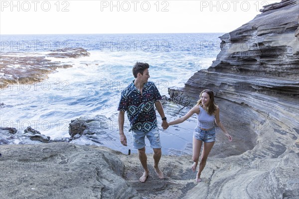 Smiling couple walking on rock formations at beach