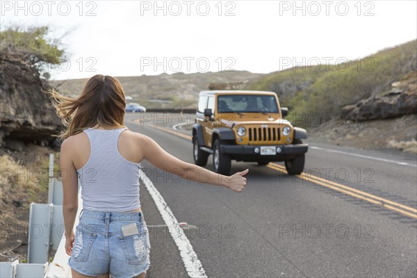 Mixed Race woman hitchhiking on road